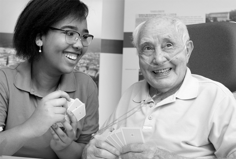 Eine junge Frau spielt mit einem lteren Mann im Krankenhaus Karten