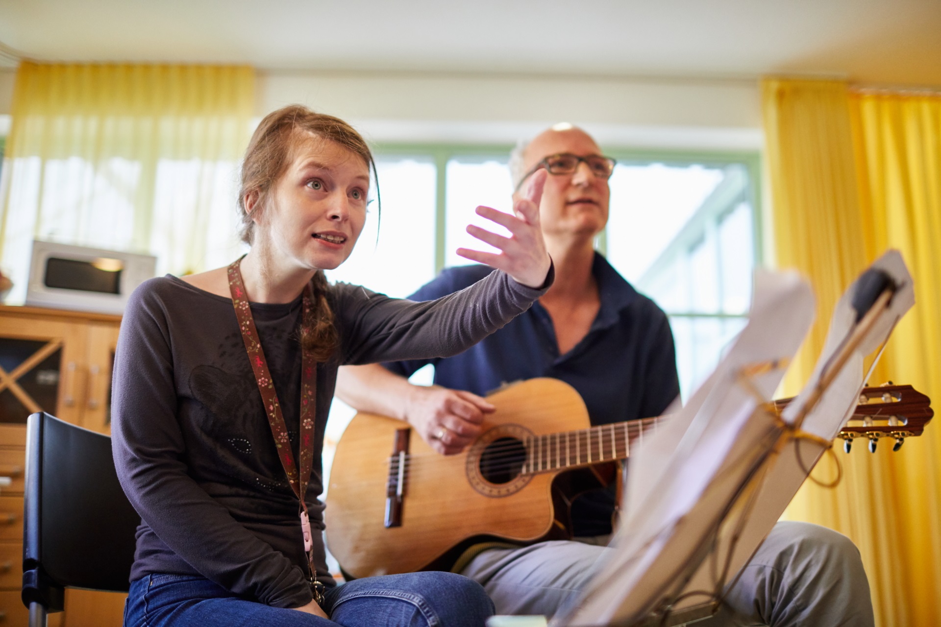Ein Musik-Therapeut mit Gitarre und eine junge singende Klientin